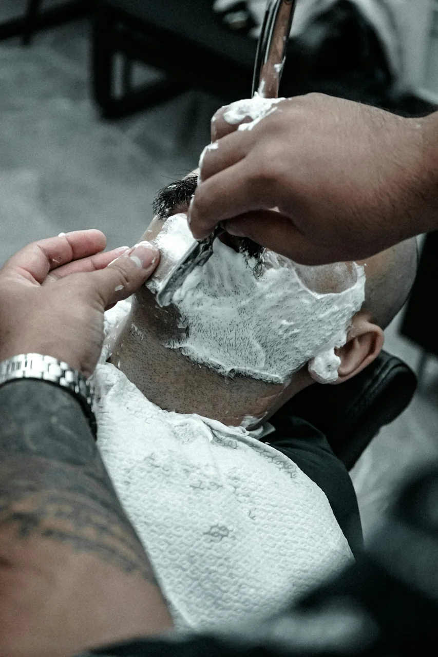 A barber carefully detailing a client’s haircut